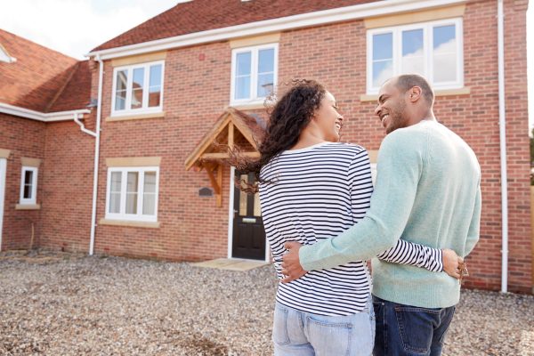 Rear,View,Of,Couple,Standing,Outside,New,Home,On,Moving