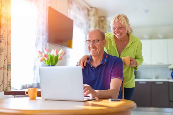 Senior,Couple,Looking,At,The,Lap,Top,Screen,Smiling,And