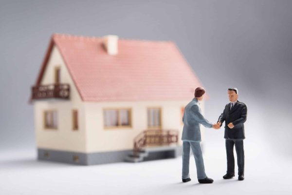 Two,Businessmen,Shaking,Hands,In,Front,Of,A,House