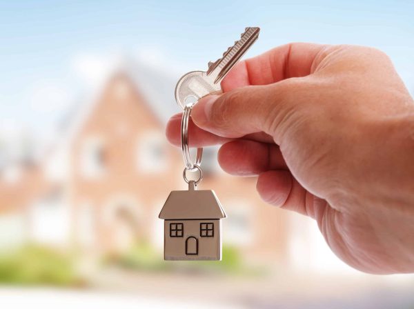Holding,House,Keys,On,House,Shaped,Keychain,In,Front,Of