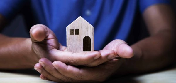 Wooden,Toy,House,Protected,By,Hands.,Home,Insurance,Concept